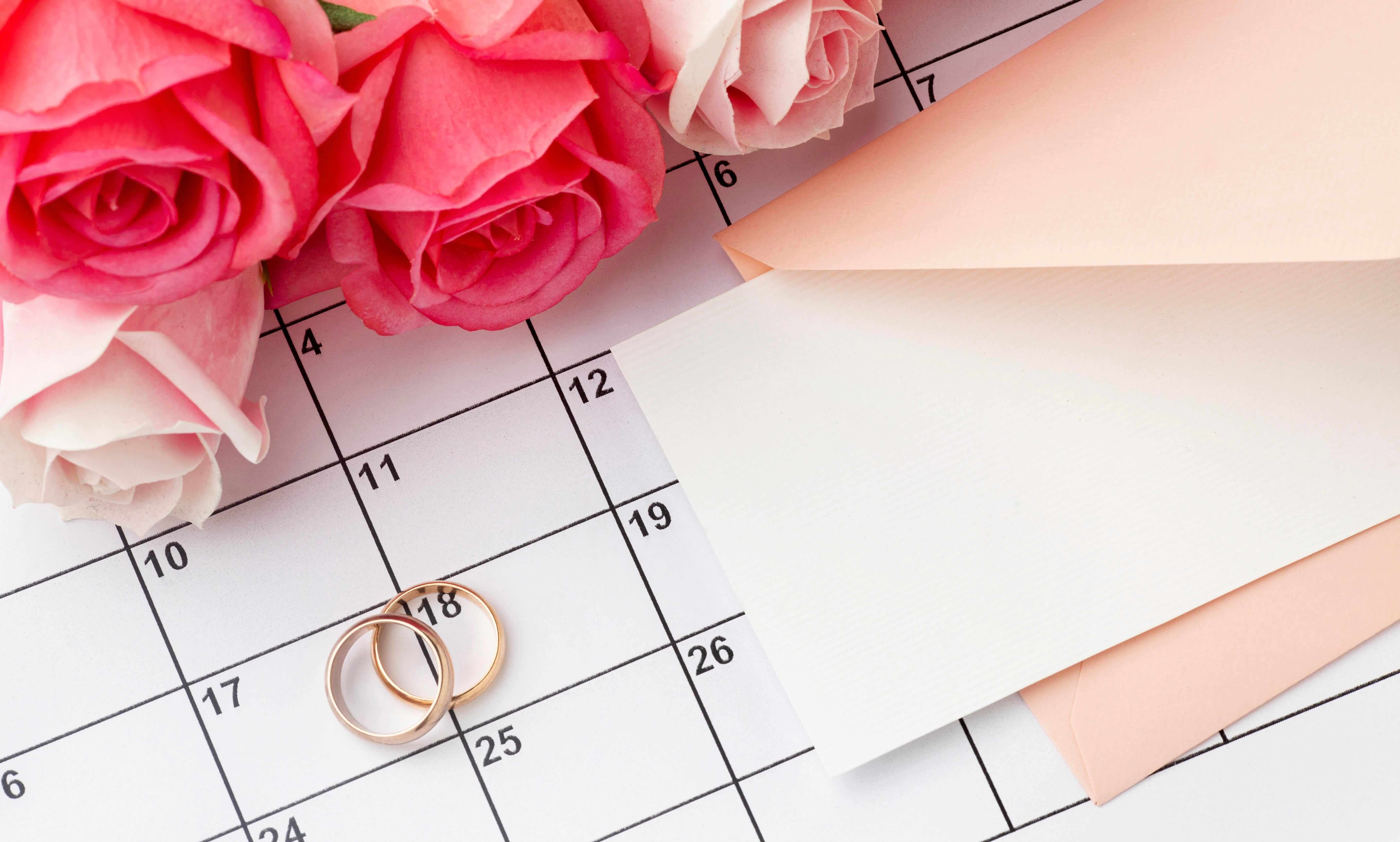 Couple reviewing wedding planning timeline at a table with notebook and laptop